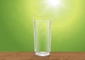 Fresh glass of drinking water on wooden tabletop on blurred green nature bokeh background Royalty Free Stock Photo