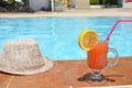 Fresh glass of water-melon smoothie drink with sunglasses, straw hat and slippers on border of a swimming pool - holiday Royalty Free Stock Photo