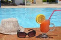 Fresh glass of water-melon smoothie drink with sunglasses, straw hat and slippers on border of a swimming pool - holiday Royalty Free Stock Photo