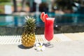 Fresh glass of watermelon smoothie drink and tropical plumeria flower standing near swimming pool - holiday vacation concept Royalty Free Stock Photo