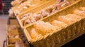 fresh golden breads with melted cheese wrapped in plastic wrap in wicker basket in bread department of supermarket Royalty Free Stock Photo