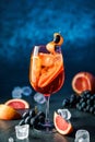 Fresh grapefruit cocktail with orange, grapes and ice in wineglass on dark blue background. Summer cold drink and cocktail Royalty Free Stock Photo