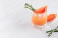 Fresh grapefruit juice with ice, piece and green rosemary on soft white wood table background. Royalty Free Stock Photo