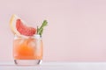 Fresh grapefruit juice with ice, piece and green rosemary on soft white wood table and pink background. Royalty Free Stock Photo