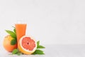 Fresh grapefruit juice and slice grapefruits with green leaves on white wood table, copy space. Royalty Free Stock Photo