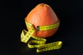 Fresh grapefruit wrapped with measuring tape. The concept of healthy nutrition, weight loss, dietetics