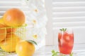 Fresh grapefruits and glass of grapefruit juice with ice on rustic white wooden table opposite the blinds Royalty Free Stock Photo