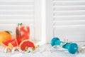 Fresh grapefruits and grapefruit juice, dumbbell and measuring tape, on rustic white wooden table opposite the blinds, fitness Royalty Free Stock Photo