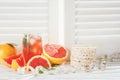 Fresh grapefruits and grapefruit juice, rice cakes and measuring tape, on rustic white wooden table opposite the blinds, fitness