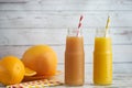 Fresh grapefruits, orange and two glasses of grapefruit and orange juice on light wooden table Royalty Free Stock Photo