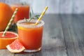 Fresh grapefruits and two glasses of grapefruit juice on grey wooden table. With copy space Royalty Free Stock Photo