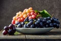 Fresh grapes. Bunches of different varieties in a plate on an old wooden table and dark background.