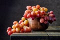 Fresh grapes. Bunches of different varieties in a plate on an old wooden table and dark background. Royalty Free Stock Photo