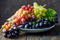 Fresh grapes. Bunches of different varieties in a plate on an old wooden table and dark background. Royalty Free Stock Photo