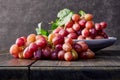 Fresh grapes. Bunches of different varieties in a plate on an old wooden table and dark background. Royalty Free Stock Photo