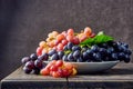 Fresh grapes. Bunches of different varieties in a plate on an old wooden table and dark background. Royalty Free Stock Photo