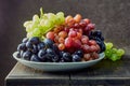 Fresh grapes. Bunches of different varieties in a plate on an old wooden table and dark background. Royalty Free Stock Photo