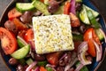 Fresh greek salad with tomato, cucumber, bel pepper , olives and feta cheese on black plate, top view, dark background Royalty Free Stock Photo