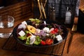 Fresh greek salad with tomato, radish, onion, bel pepper , olives and feta cheese on black plate, side view, wooden background Royalty Free Stock Photo