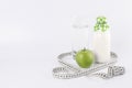 Fresh green apple, glass of water, yogurt, centimeter tape on a light background. Royalty Free Stock Photo