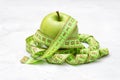 Fresh green apple with a measuring tape on a concrete table. Diet and weight loss concept Royalty Free Stock Photo