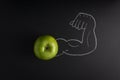 Fresh green apple and a strong arm showing its biceps muscle drawn in the black background Royalty Free Stock Photo