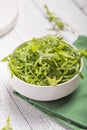 Fresh green arugula leaves on white bowl, rucola rocket salad on wooden rustic background with place for text. Selective focus, Royalty Free Stock Photo