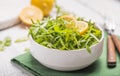 Fresh green arugula leaves on white bowl, rucola rocket salad on wooden rustic background with place for text. Selective focus, Royalty Free Stock Photo