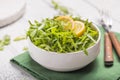 Fresh green arugula leaves on white bowl, rucola rocket salad on wooden rustic background with place for text. Selective focus, Royalty Free Stock Photo