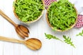 Fresh green arugula leaves on wooden bowl, rucola salad on white wooden rustic background top view with place for text. Rocket Royalty Free Stock Photo