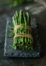 fresh green asparagus bound together with twine on a stone plate