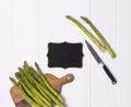 Fresh green asparagus on cutting board with knife at white wooden table background Royalty Free Stock Photo