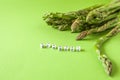 Fresh green asparagus on green background with copy space and cube letters