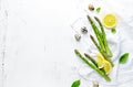 Fresh green asparagus, lemon and quail eggs on white wooden background. Symbolic image. Flat lay.