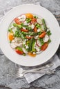 Fresh Green Asparagus salad witch goat cheese, green peas, radish and tomato closeup on the plate. Vertical top view Royalty Free Stock Photo