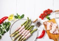 Fresh green asparagus wrapped in bacon on white wooden table. Top view Royalty Free Stock Photo