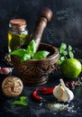 Fresh green basil in wooden mortar and pestle with garlic olive oil salt and pepper on dark background with copy space Royalty Free Stock Photo