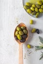 Fresh green and black olives in spoon on white wooden background. Royalty Free Stock Photo