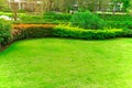 Fresh green Burmuda grass smooth lawn as a carpet with curve form of bush, trees on the background, good maintenance lanscapes in Royalty Free Stock Photo
