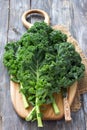 Fresh green curly kale leaves on a cutting board on a wooden table