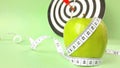 Fresh green fruits wrapped in a measuring tape on a dart background.Concept of the goal to lose weight,the goal of diet