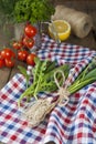 Fresh green garlic spears and arugula on napkin with tomatoes and lemon