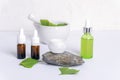 Fresh green ginkgo leaves, cream jar on a natural stone, brown glass bottles with essential oil, face serum bottle and Royalty Free Stock Photo