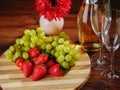 Fresh green grapes and red strawberry on a wooden board, Two champagne flutes  and a bottle of champagne without label, Royalty Free Stock Photo
