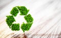 Fresh green leaf recycle symbol on wooden desk with blurred back