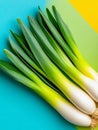 Fresh green leeks lie on a vibrant blue, green and yellow background Royalty Free Stock Photo