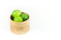 Fresh green limes in the bamboo basket isolated on white background Royalty Free Stock Photo