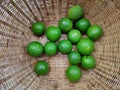 Fresh green limes in the small colorful baskets on the woven bamboo plate. The Thai traditional fresh market Royalty Free Stock Photo