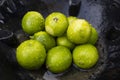 Fresh Green Limes with Water Droplets in a Rustic Setting. Royalty Free Stock Photo