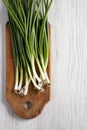 Fresh green onions on a cutting board on a white wooden table, top view. From above, overhead, flat lay. Copy space Royalty Free Stock Photo